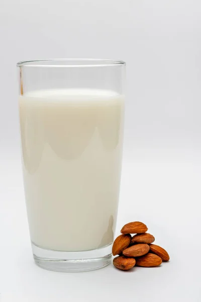アーモンドナッツの白い背景にアーモンドミルクのグラス — ストック写真