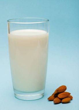 badem fıstığı ile mavi arka planda badem sütü bir bardak