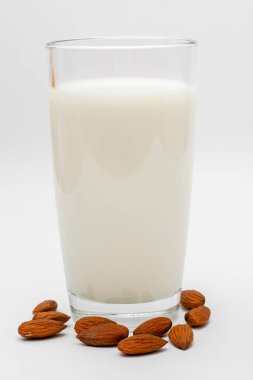 badem fıstığı ile beyaz arka planda badem sütü bir bardak