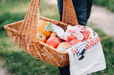 adam bahçede meyve, elma ve işlemeli masa örtüsü ile bir hasır sepet tutar