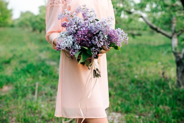 girl in the garden in a lilac dress holding a bouquet of lilacs