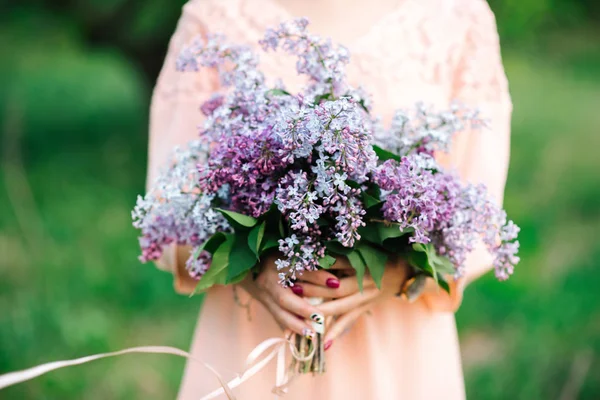 girl in the garden in a lilac dress holding a bouquet of lilacs