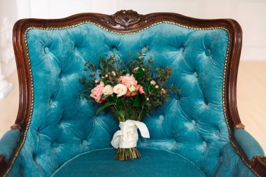 Mavi bir eski koltukta düğün buketi.