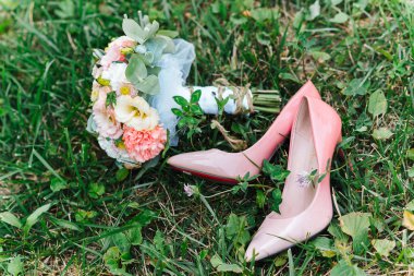 Düğün buketi ve çimlerin üzerinde gelinin ayakkabıları.