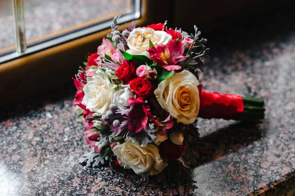 大理石の窓の上の花嫁の花束に結婚指輪 — ストック写真