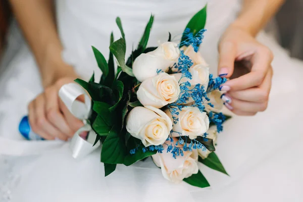 白いドレスを着た花嫁が座って 彼女の手に白いバラの結婚式の花束を持っている — ストック写真