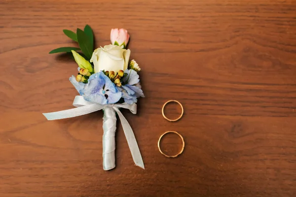 木製のテーブルの上の新郎と結婚指輪のためのバラのブトニエール — ストック写真