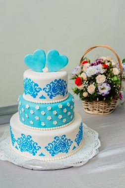 beyaz bir masa örtüsü ile masada çiçek bir buket ile sakız yapılmış mavi düğün pastası