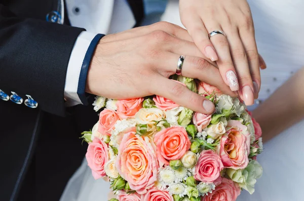 ブライダルブーケに指輪を持つ新婚夫婦を手にする — ストック写真