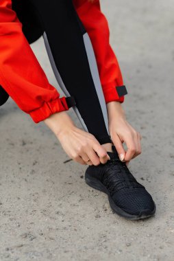 Yaz ormanı patikasında koşmadan önce bağcıklarını bağlayan genç bir kız.