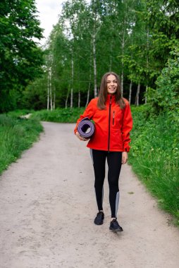 Kırmızı ceketli genç bir kız doğada eğitime gider.