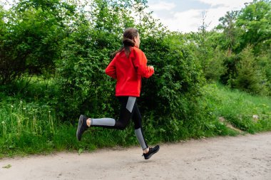 Doğada koşan kırmızı ceketli genç kız.