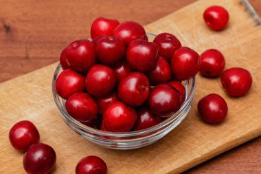 Tahta tahtada, ahşap zeminde cam tabakta taze siyah kirazlar.