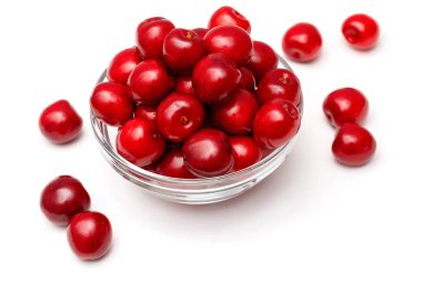 Beyaz arka planda cam bir tabakta taze siyah kirazlar.