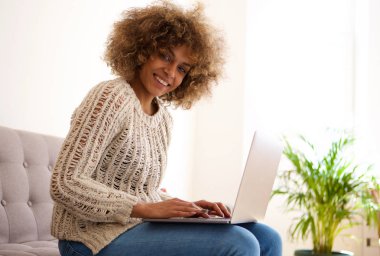 Laptop ile evde oturan güzel genç Afro-Amerikan kadın portresi