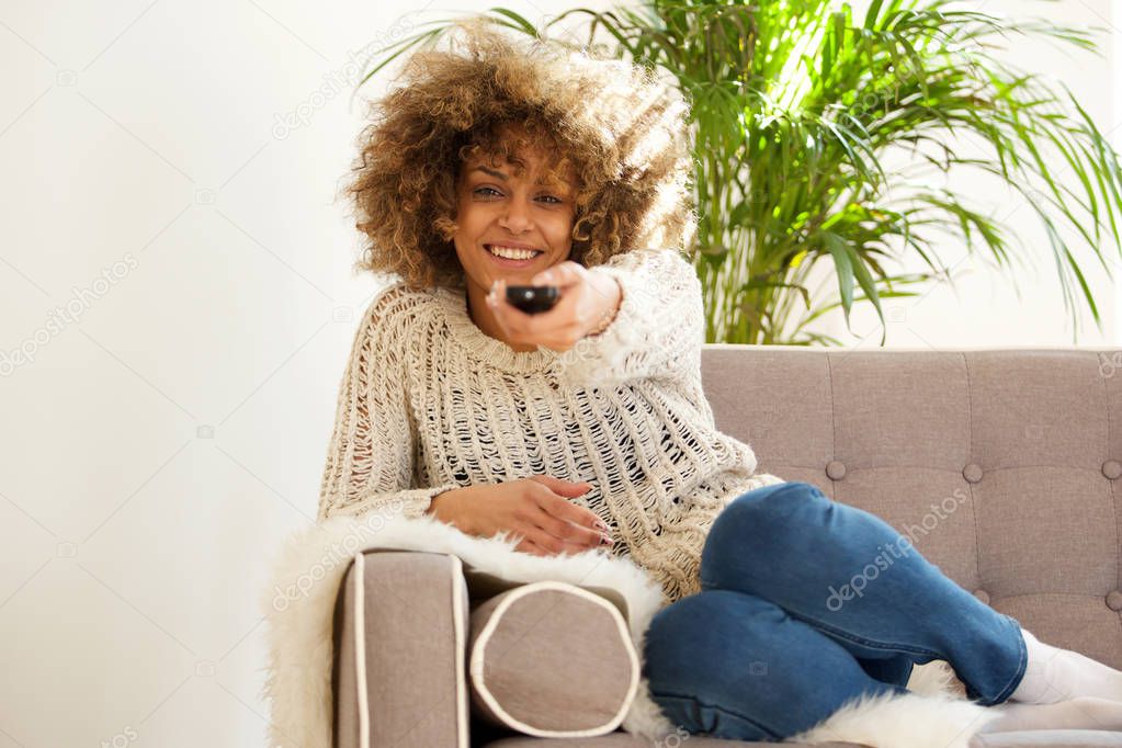 Portrait of african american woman smiling with tv remote control