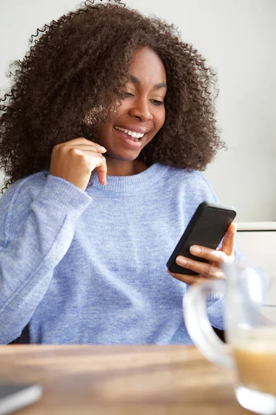 Masada oturan ve cep telefonuna kısa mesaj okuma genç siyah kadın portresi