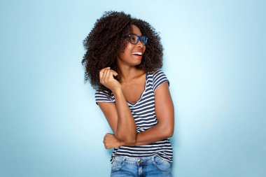 Mavi zemin üzerine gözlük ile gülümseyen genç Afro-Amerikan kadın portresi
