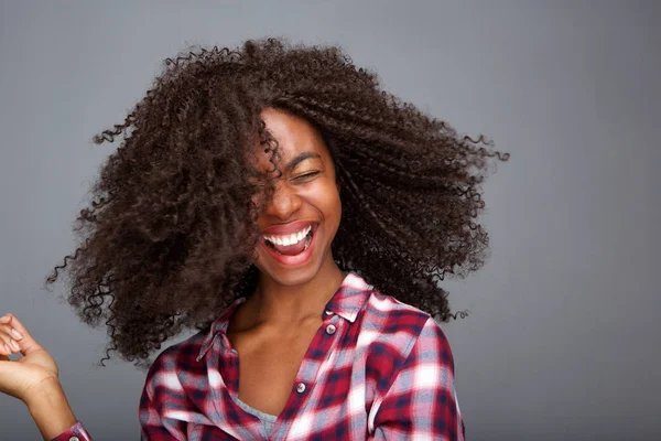 Kıvırcık saçları gri arka plan üzerinde gülüyor uçan ile neşeli kız portresi kapatın