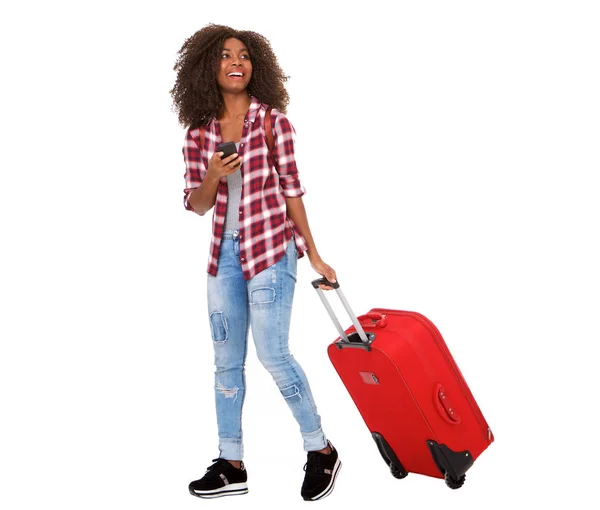 白い背景の上のスーツケースと電話で歩いている美しい若いアフリカ系アメリカ人女性の全身肖像画 — ストック写真
