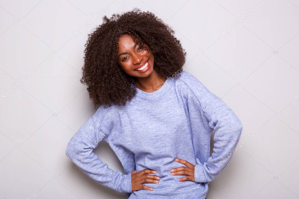 Portrait of happy young african american woman standing with hands on hips against white background