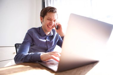 Cep telefonu üzerinde konuşurken ve dizüstü bilgisayarda çalışma neşeli adam portresi