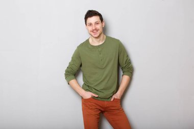 Gri arka planı gülümseyen çekici genç adam portresi