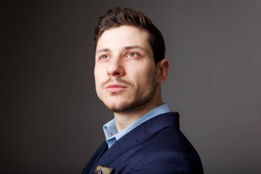 Gri arka planı bakarak yakışıklı genç işadamı portresi kapatın 