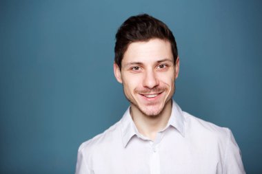 Mavi arka planı gülümseyerek mutlu bir genç adam portresi kapatın