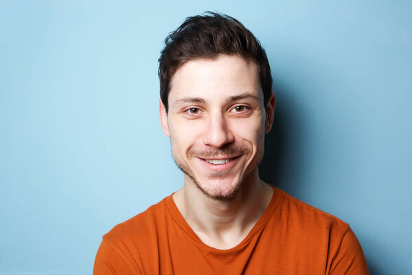 Close up horizontal portrait of handsome young man against blue background