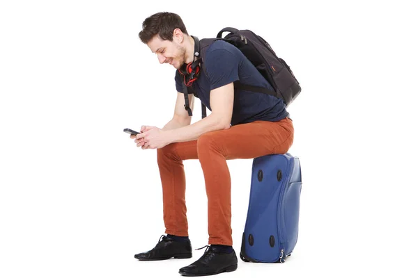 幸せな男性旅行者のスーツケースの上に座って 携帯電話を見ての肖像画 — ストック写真