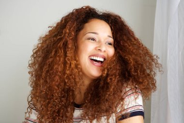 Kıvırcık saçlı gülen ile mutlu genç Afro-Amerikan kadın portresi kapatın