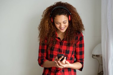 Cep telefonu tutarak ve kulaklık ile müzik dinlemek mutlu genç kadın portresi