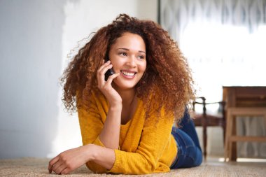 Cep telefonu üzerinde konuşurken kıvırcık saçlı mutlu genç kadın portresi