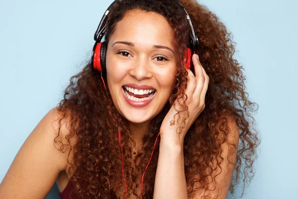 青い背景でヘッドフォンで音楽を聴く幸せな若い女の肖像 — ストック写真