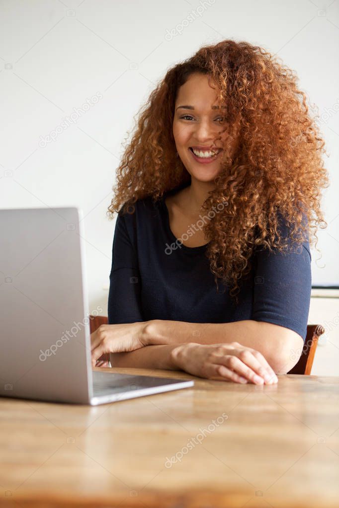 Portrait of young woman sitting with laptop