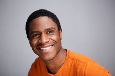 Gri arka planı gülümseyen genç siyah adam portresi kapatın