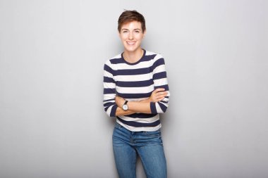 Gri bir arka plana dayanır kısa saçlı genç gülümseyen kadın portresi