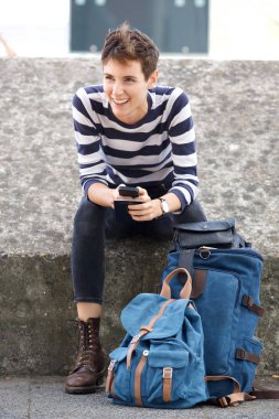 Mutlu genç kadının cep telefonu ve paket ile açık havada oturma portre