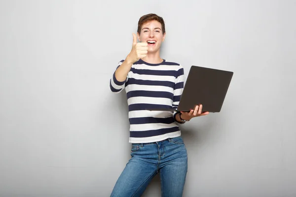 Portrait of cool young woman holding laptop and with thumbs up hand sign