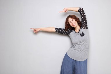 Kopya alanı gri arka plan üzerinde parmakları işaret mutlu genç kadın portresi