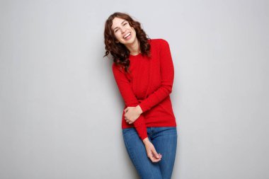 Kırmızı kazaklı tarafından gri arka plan gülerek mutlu genç kadın portresi