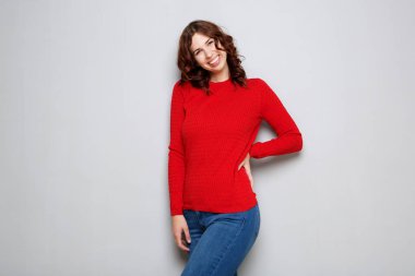 Kırmızı kazaklı gri duvar tarafından gülerek mutlu genç kadın portresi