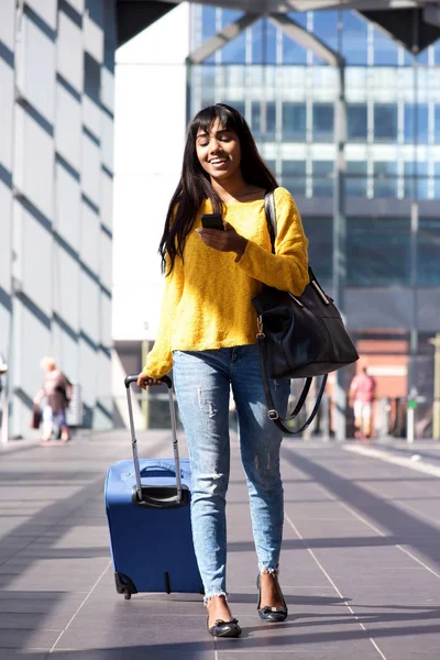 Tam vücut istasyonunda çanta ve cep telefonu ile yürüyen Genç Hintli kadın portresi