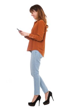 Tam uzunlukta yan yürüyüş ve izole beyaz arka plan üzerinde cep telefonu arayan genç bir kadın portresi