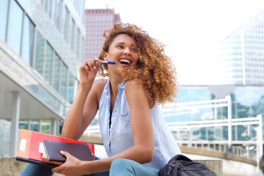 Dışarıda kalem ve kitap ile gülen kız öğrenci portresi