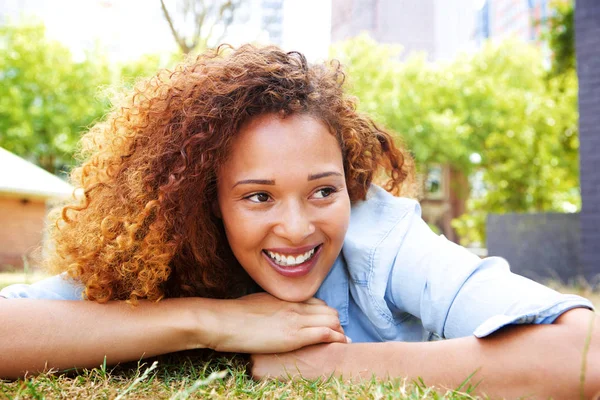 公園と笑顔で草の上に横たわる若い女性の肖像画 — ストック写真