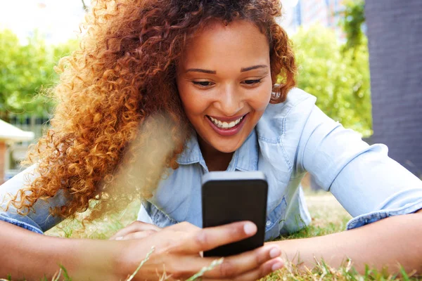 Porträtt Glad Ung Kvinna Ligga Gräset Och Tittar Mobiltelefon — Stockfoto