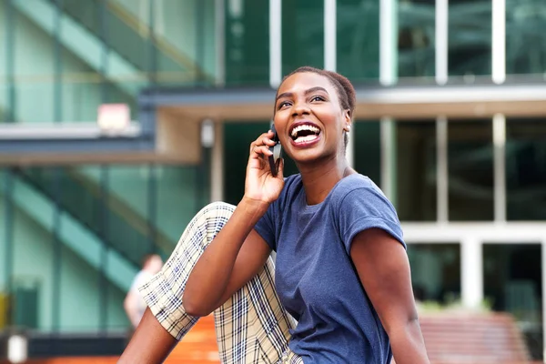 Side portrait of happy young african american woman talking with cellphone outdoors