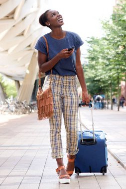 Tam vücut City çanta ve cep telefonu ile yürüyen genç Afro-Amerikan kadın portresi